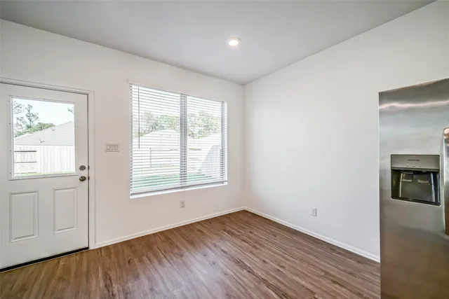 an empty room with wooden floor cabinet and windows