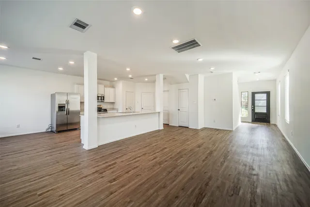 a view of an empty room and kitchen with kitchen island