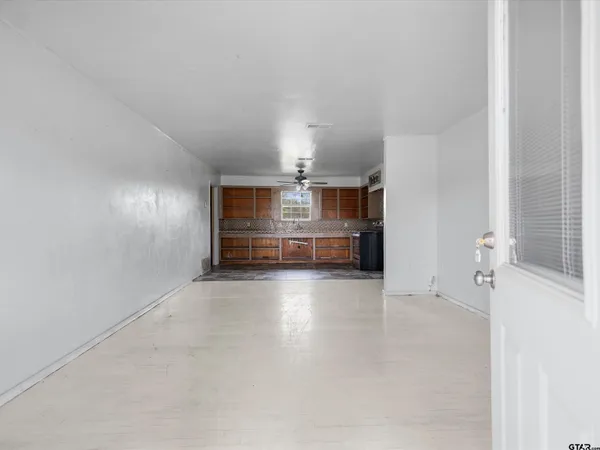 an empty room with windows and ceiling fan
