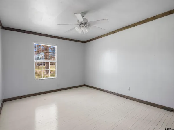 an empty room with a ceiling fan and a window