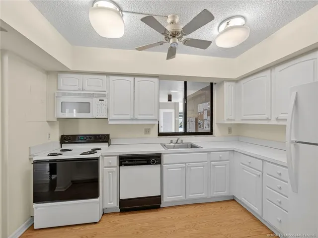a kitchen with white cabinets and white appliances