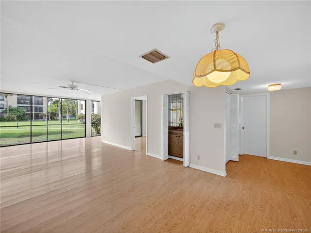 a view of an empty room with wooden floor and windows