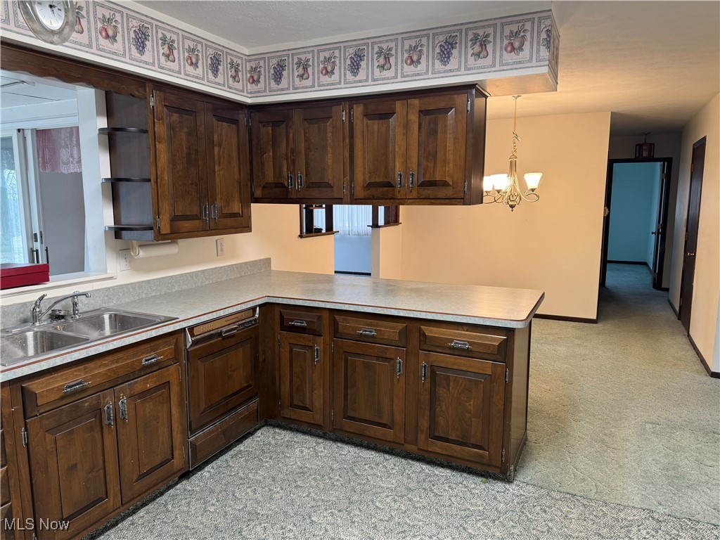 68697 Morristown Flushing Road Flushing, OH 43977 - Photo 13 of 33 Kitchen with a peninsula, light countertops, dark brown cabinets, pendant lighting, and a sink