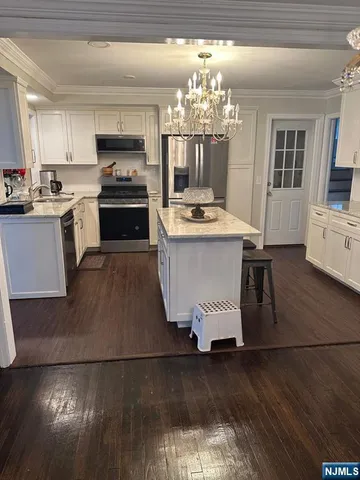 a kitchen with stainless steel appliances granite countertop a stove top oven a sink dishwasher and a dining table with wooden floor