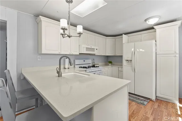 a kitchen with stainless steel appliances a refrigerator a sink dishwasher a stove and white cabinets with wooden floor