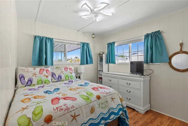 a bedroom with a bed a dresser and painting on the wall