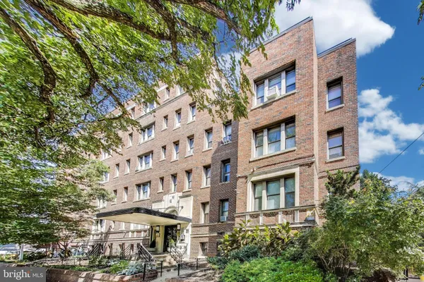 a front view of a building with a lot of plants and trees