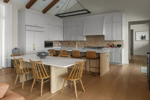 a kitchen with a dining table chairs and white cabinets