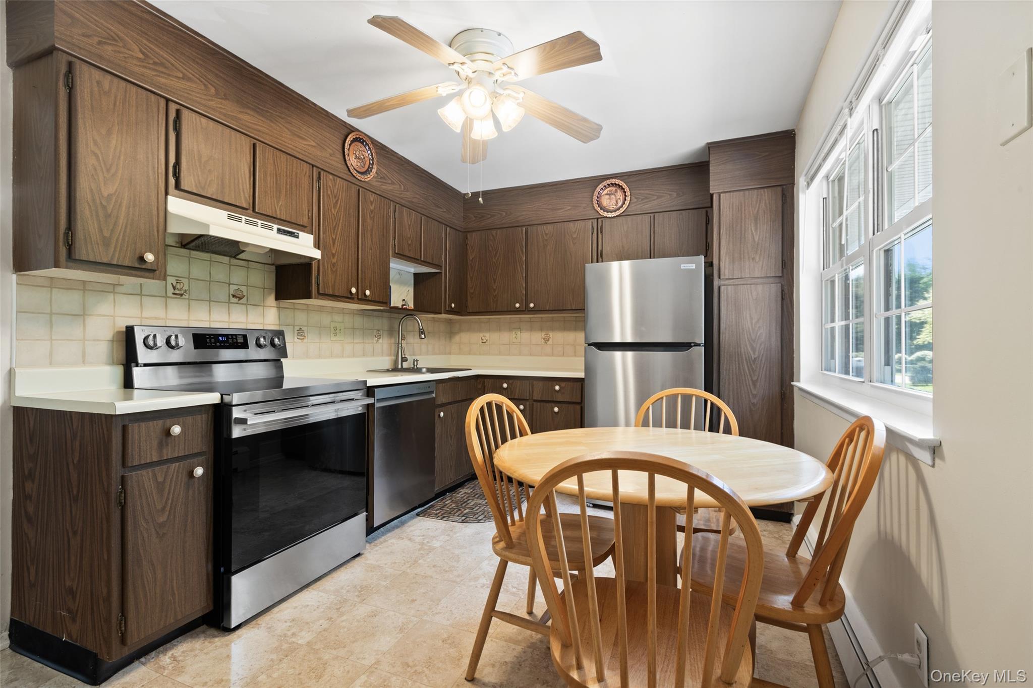 1840 Crompond Road, Unit 5C2 Peekskill, NY 10566 - Photo 9 of 27 a kitchen with stainless steel appliances granite countertop a dining table chairs refrigerator sink and cabinets