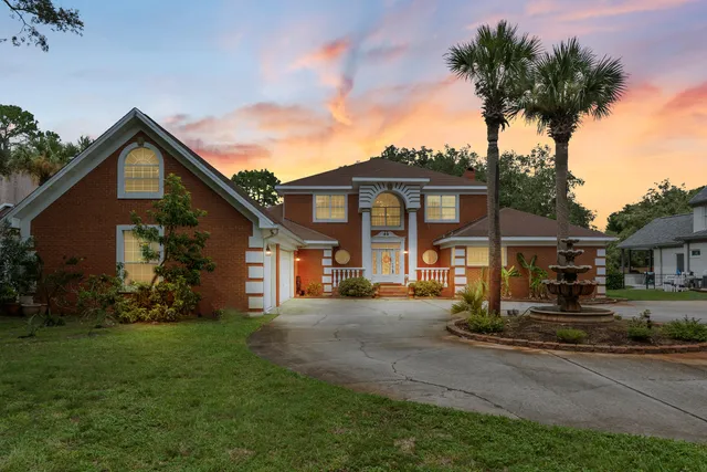 a front view of a house with a garden and trees