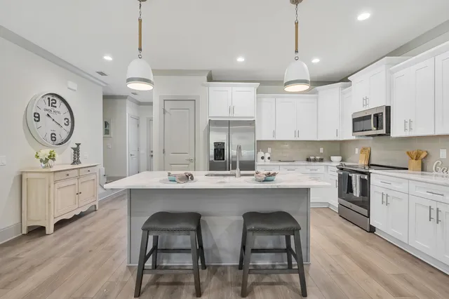 a living room with furniture white walls and kitchen view