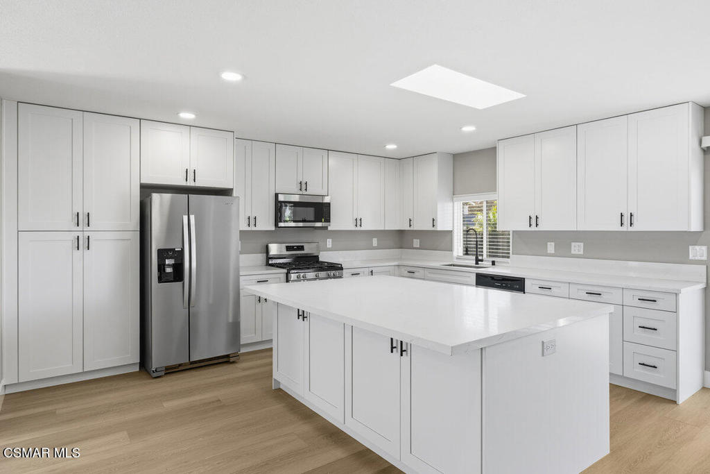 1069 Donner Avenue Simi Valley, CA 93065 - Photo 3 of 24 a kitchen with white cabinets and stainless steel appliances