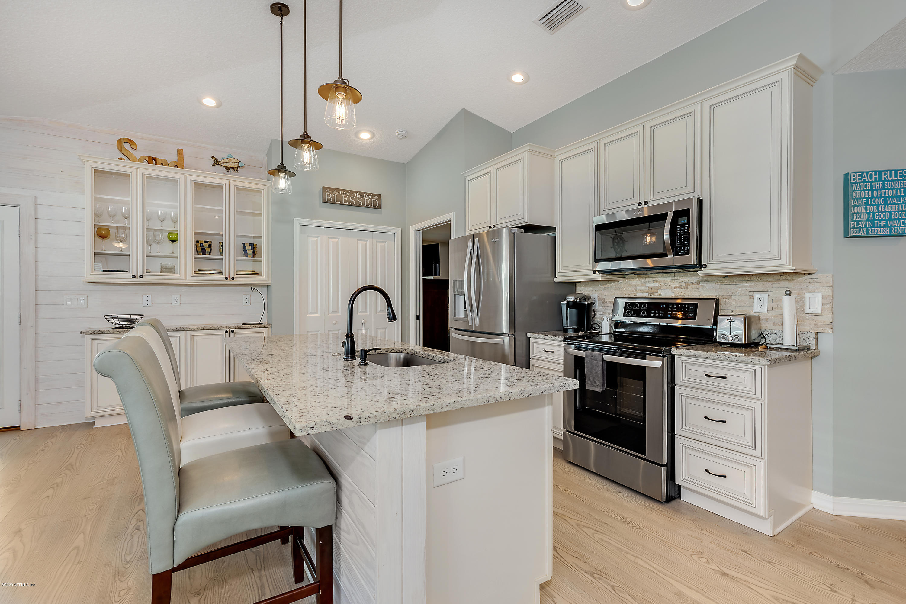 405 2nd Street St. Augustine, FL 32084 - Photo 11 of 32 a kitchen with stainless steel appliances granite countertop a stove a sink a refrigerator a microwave oven with white cabinets and wooden floor