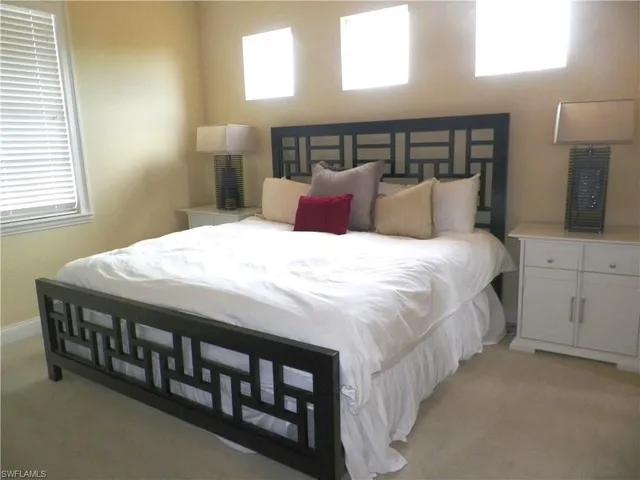 a large bed sitting in a bedroom next to a window