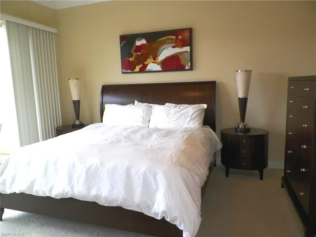 a large bed in a bedroom next to a window