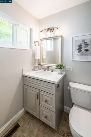 a bathroom with a granite countertop toilet sink and mirror