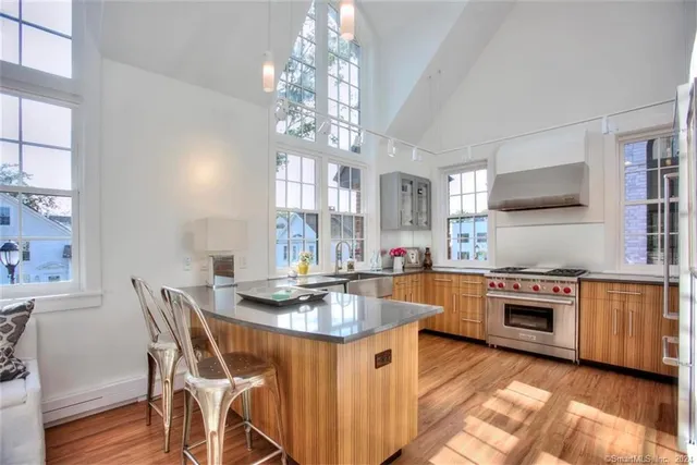 a kitchen with stainless steel appliances granite countertop a stove top oven a sink dishwasher a dining table and chairs with wooden floor