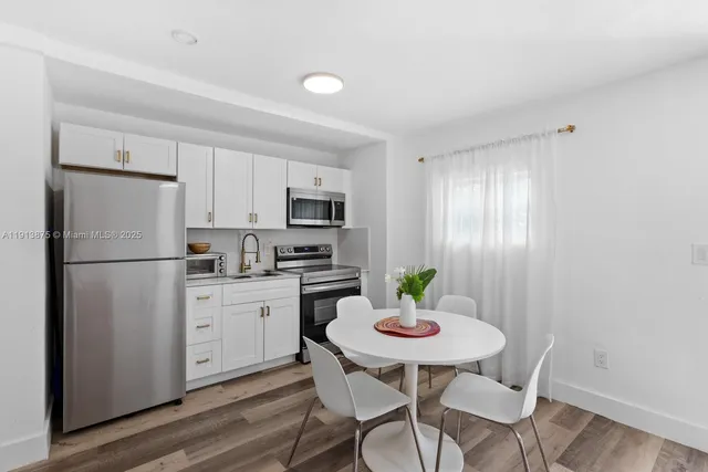 a kitchen with a refrigerator white cabinets and microwave