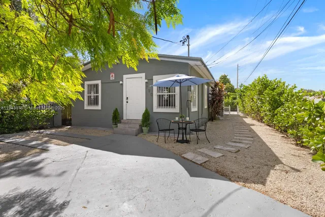 a patio with table and chairs and potted plants