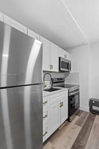 a kitchen with stainless steel appliances granite countertop a refrigerator a stove a sink and a microwave