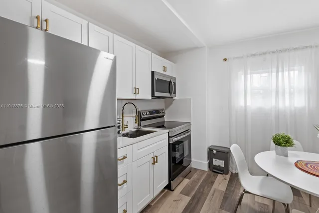 a kitchen with stainless steel appliances granite countertop a refrigerator a sink a stove a dining table and chairs