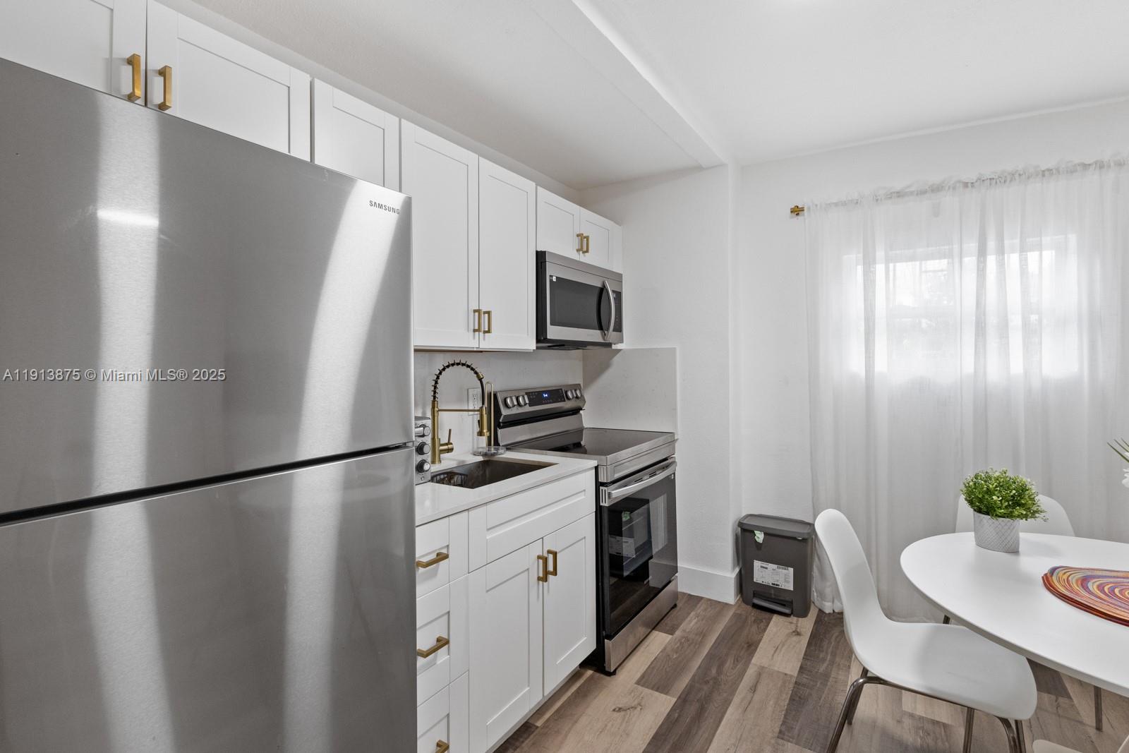 790 Northwest 60th Street Miami, FL 33127 - Photo 34 of 35 a kitchen with stainless steel appliances granite countertop a refrigerator a sink a stove a dining table and chairs