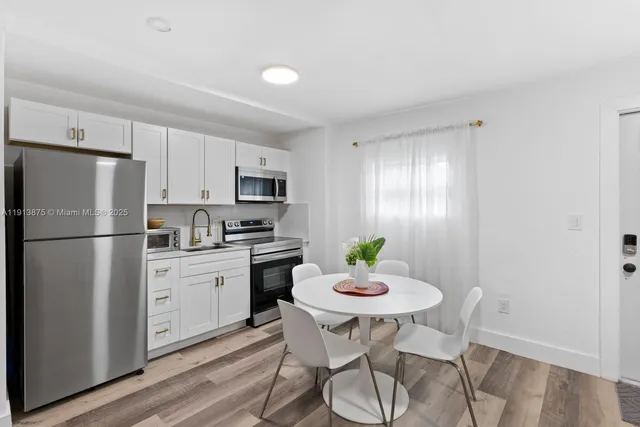 a kitchen with a refrigerator a stove a dining table and chairs with wooden floor