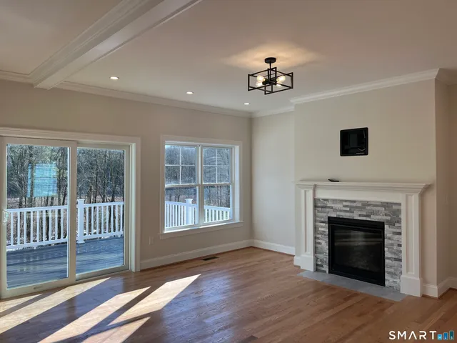 a view of an empty room with wooden floor fireplace and a window