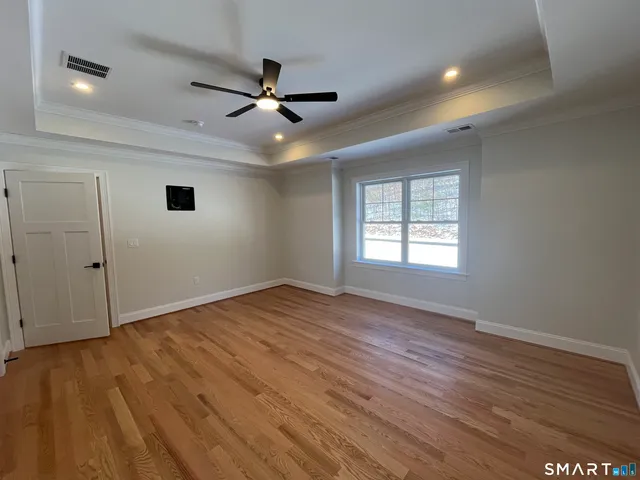 a view of empty room with wooden floor and fan