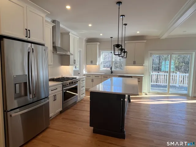 a kitchen with kitchen island a counter top space appliances and a ceiling fan