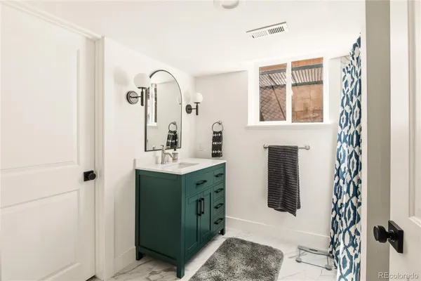 a bathroom with a granite countertop sink a mirror and shower
