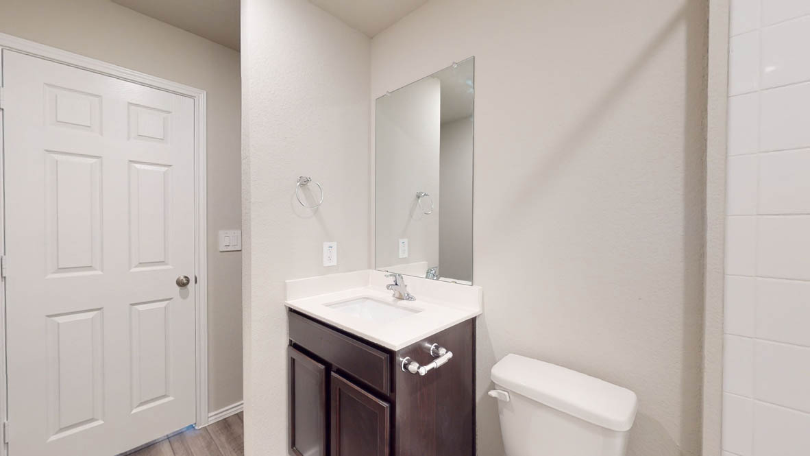 513 Hector Loop Georgetown, TX 78626 - Photo 11 of 12 A well-appointed bathroom features a dark wood vanity, integrated sink, and an elegant mirror.