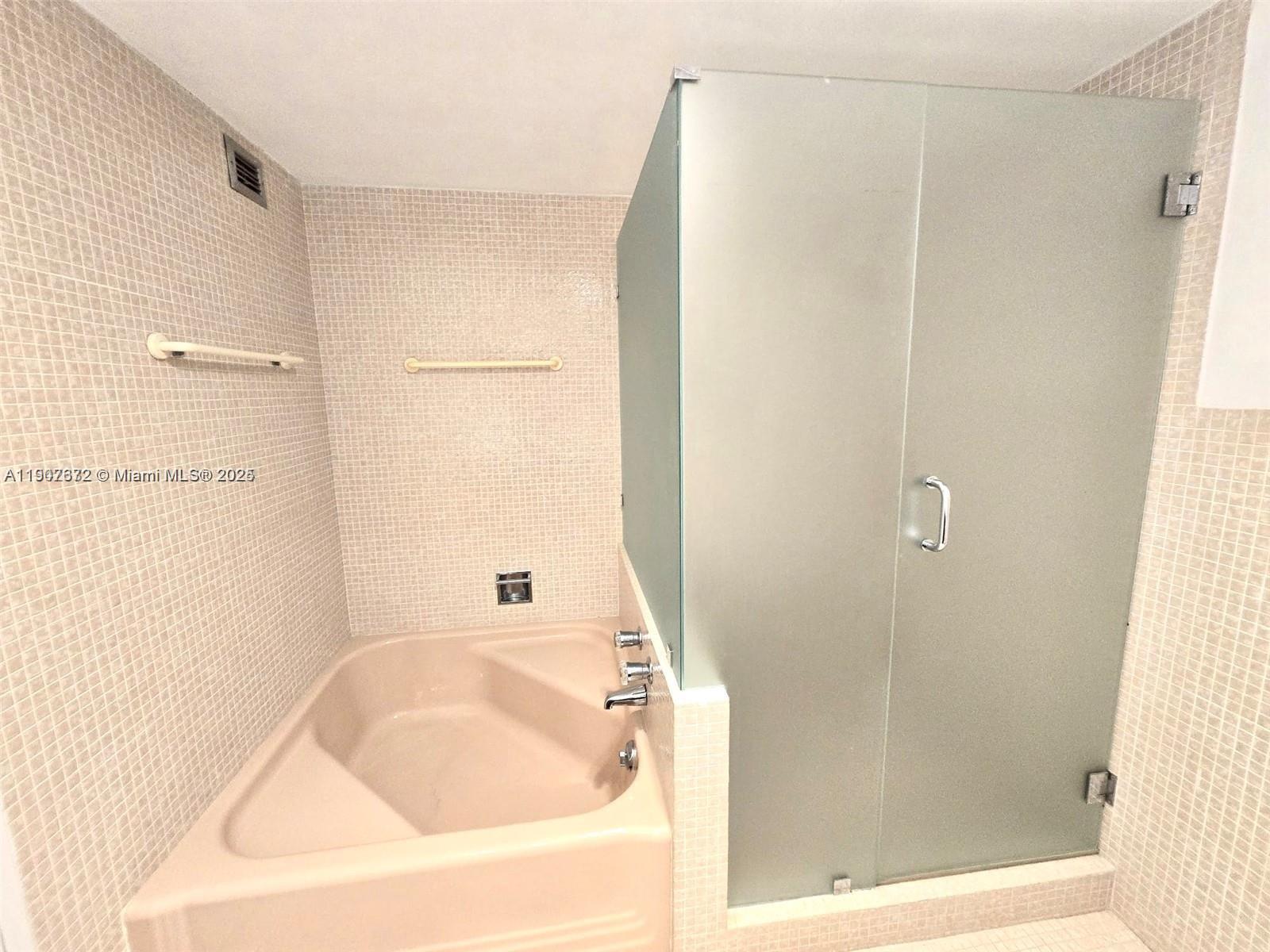 5255 Collins Avenue, Unit 7B Miami Beach, FL 33140 - Photo 11 of 12 a bathroom with a bathtub and a shower
