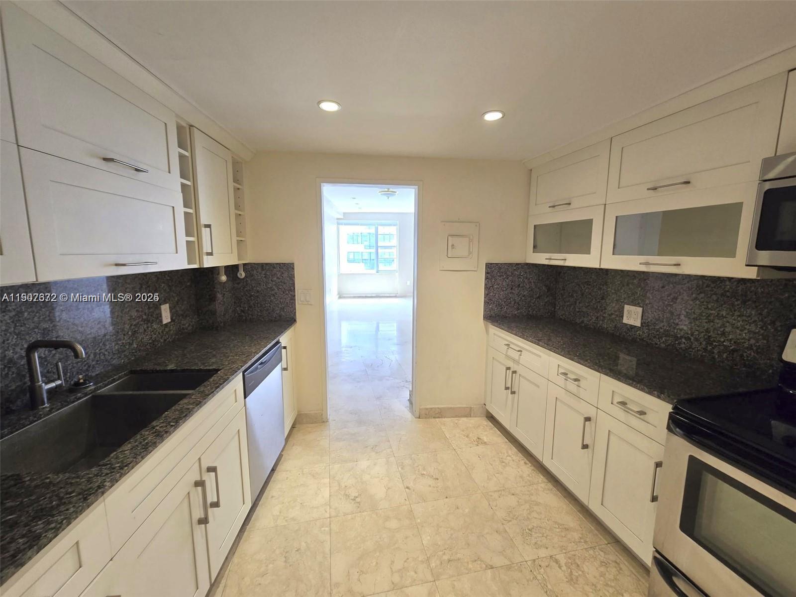 5255 Collins Avenue, Unit 7B Miami Beach, FL 33140 - Photo 8 of 12 a kitchen with stainless steel appliances a sink stove and cabinets