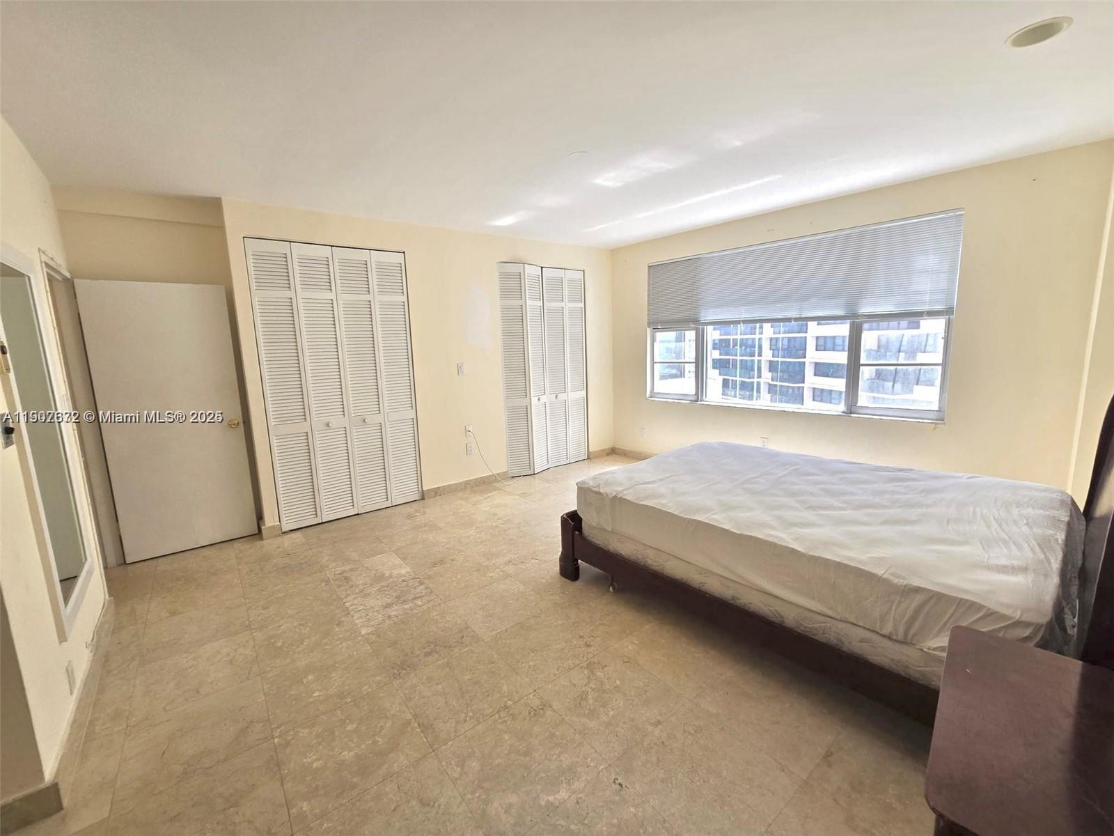 5255 Collins Avenue, Unit 7B Miami Beach, FL 33140 - Photo 9 of 12 a spacious bedroom with a bed and a window