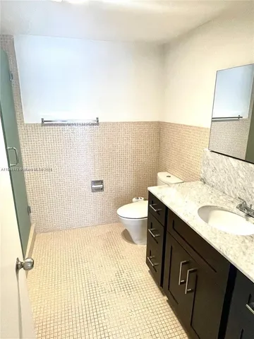 a bathroom with a granite countertop sink a toilet a mirror and shower