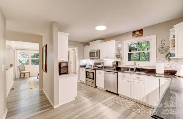 a kitchen with granite countertop white cabinets sink and stainless steel appliances