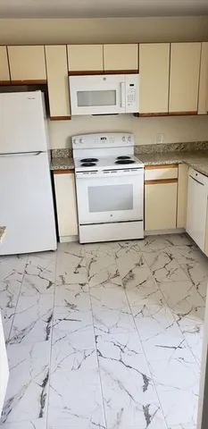 a white cabinets with granite countertop a stove a sink and white cabinets