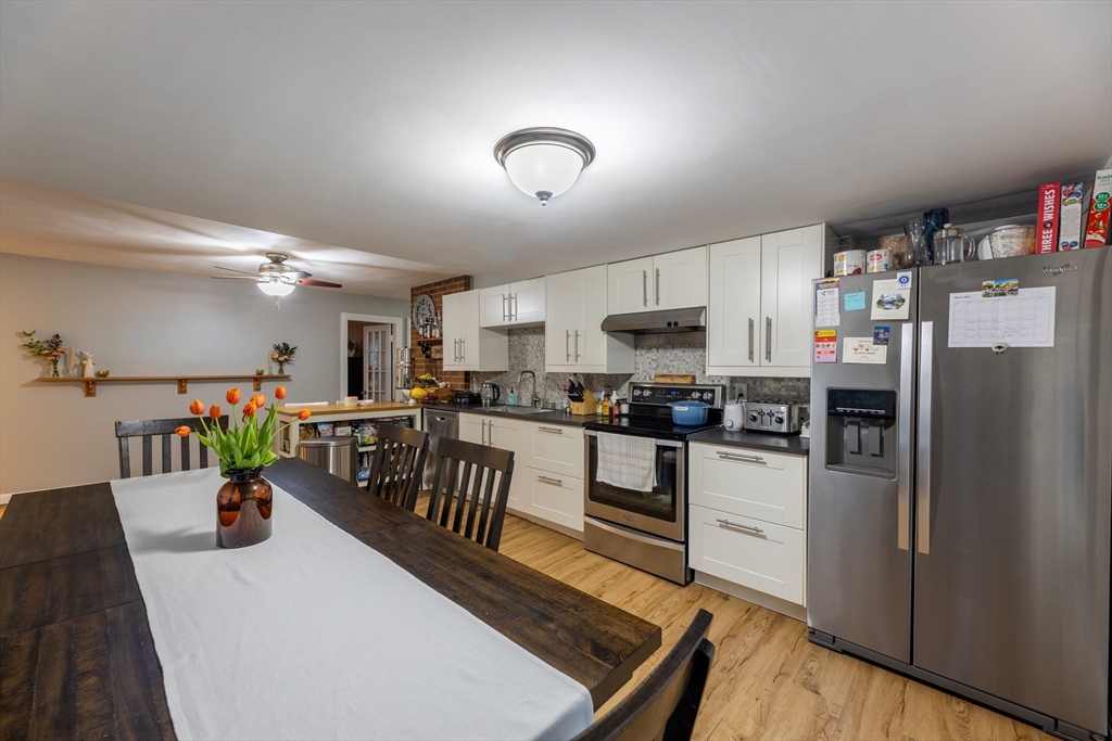 32 Farmington Street, Unit 1 Worcester, MA 01603 - Photo 4 of 25 a kitchen with stainless steel appliances a refrigerator a stove a sink dishwasher and a dining table with wooden floor