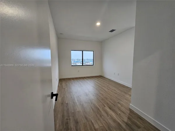 an empty room with wooden floor and windows