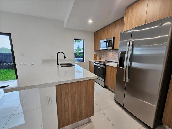 a kitchen with stainless steel appliances granite countertop a refrigerator and a sink