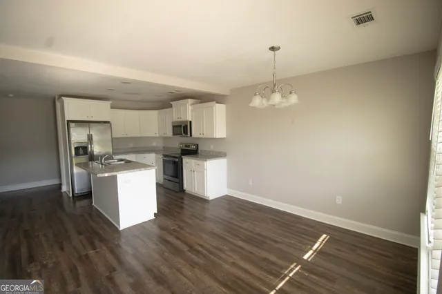 a kitchen with a refrigerator and white cabinets