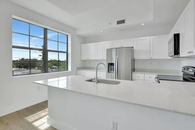 a kitchen with stainless steel appliances granite countertop a sink a stove and a refrigerator with wooden cabinets