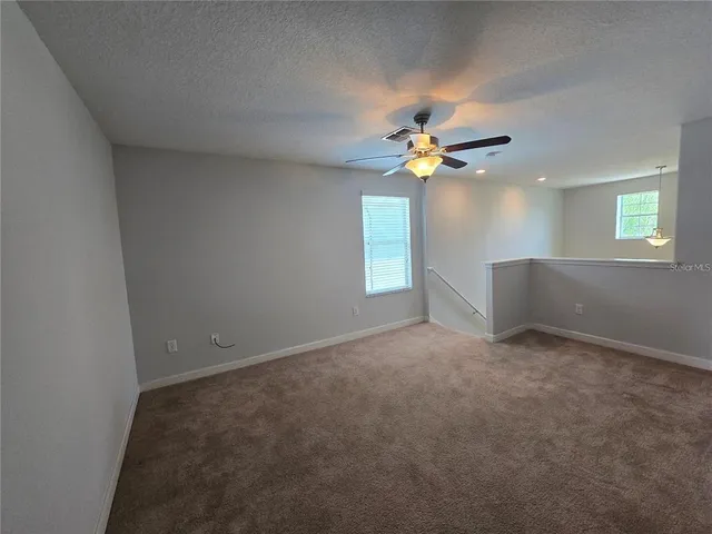 an empty room with windows and chandelier fan