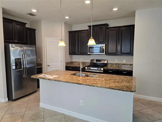 a kitchen with stainless steel appliances granite countertop a sink a stove and a refrigerator