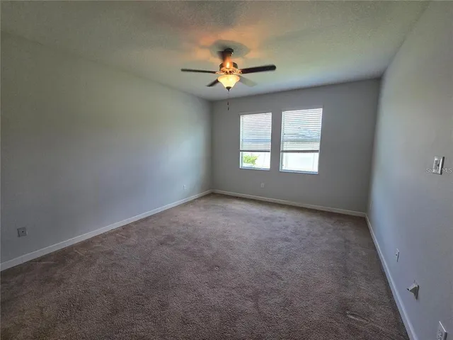 an empty room with a window and a ceiling fan