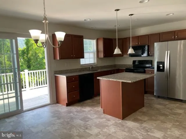 a kitchen with stainless steel appliances granite countertop a refrigerator a sink a stove and a wooden floors