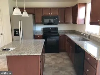 a kitchen with stainless steel appliances granite countertop a sink a stove and a refrigerator