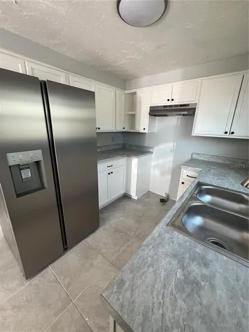 a kitchen with stainless steel appliances granite countertop a sink refrigerator and cabinets