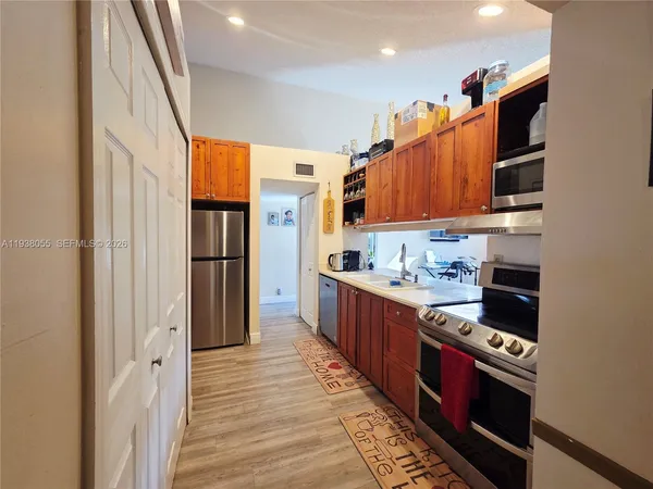 a kitchen with stainless steel appliances granite countertop a refrigerator a stove and a wooden cabinets